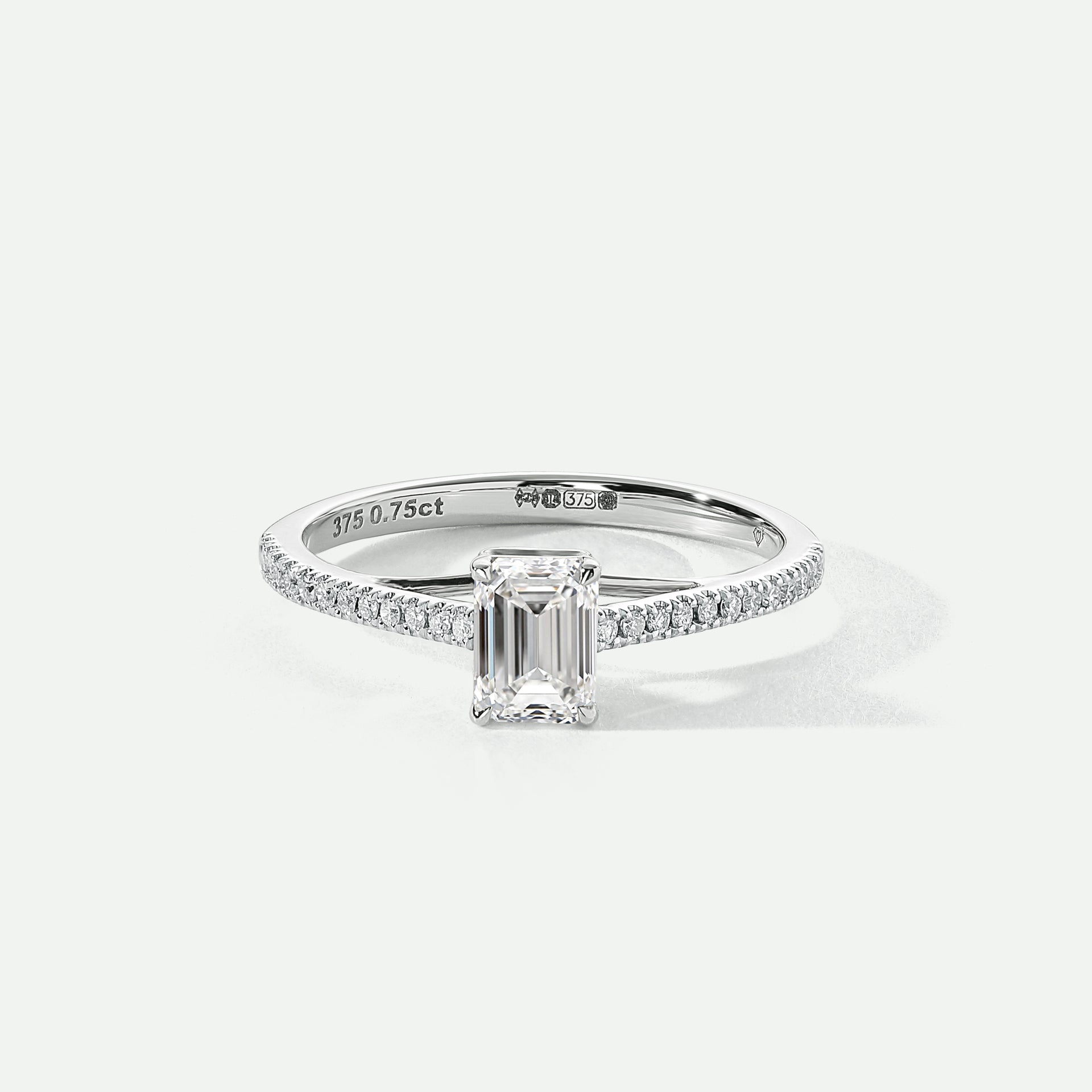 A 9ct white gold ring featuring an emerald cut lab grown diamond centerpiece with pavé set lab grown diamonds on the shoulders.