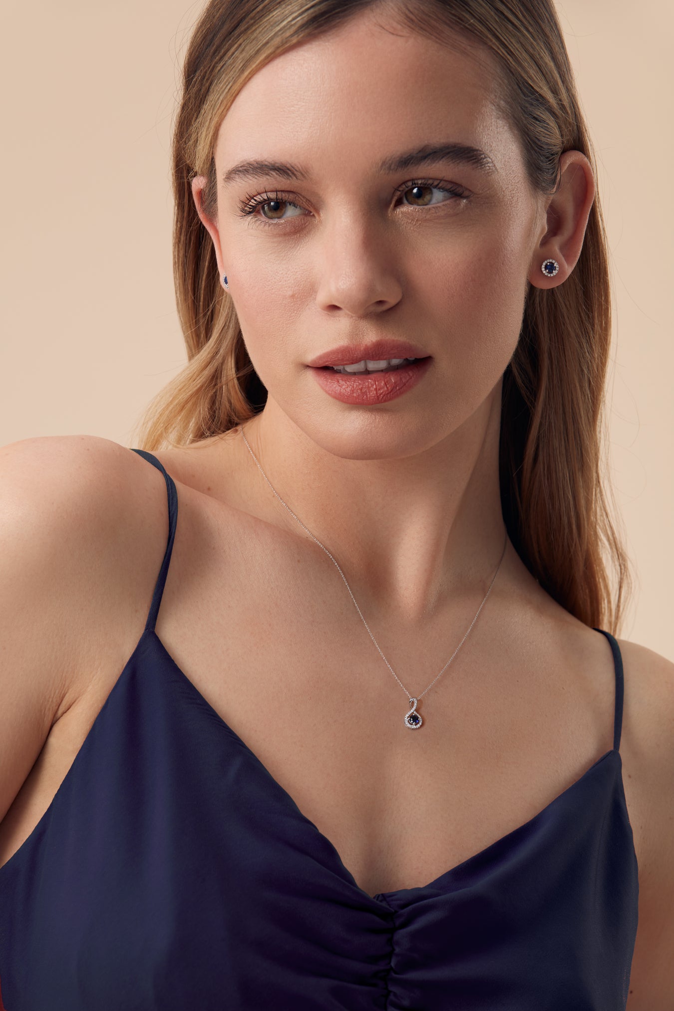Model wearing a lab grown sapphire and lab grown diamond jewellery set featuring earring studs and a necklace. 